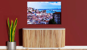 Framed cityscape wall art above wooden cabinet against red wall, with potted snake plant