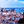Colorful cityscape with red rooftops, historic buildings, and a large ship on a blue river