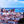 Vivid cityscape with orange rooftops, historic buildings, and blue waterfront under a bright sky