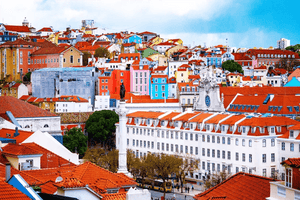 Colorful cityscape with red-roofed buildings, historic architecture, and clear blue sky
