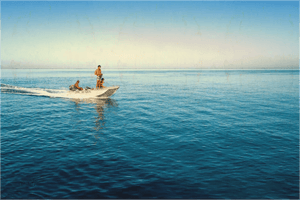 Small motorboat with three people on calm blue sea under clear sky