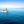 Three people riding a small motorboat on calm blue ocean under a clear sky