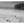 Black and white photo of a lone person walking on a deserted tropical beach with palm trees.