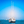 Sailboat anchored on calm blue sea under clear sky, with other boats in the background