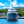 Luxury yacht docked at marina with lush green hillside and blue sky in background