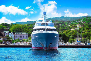 Luxury yacht in marina with lush green hillside and blue sky background