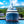 Luxury yacht docked at marina with lush green hillside and blue sky in background