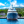 Luxury yacht docked at marina with blue sky, water, and lush green hills in background