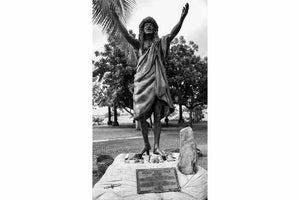 Black and white photo of Polynesian statue with arms raised, outdoor park, lush trees