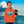 Child in orange eco-friendly hoodie with tropical ocean and hut print, standing by water