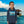 Child wearing blue eco-friendly hoodie with tropical boat print, standing by water