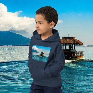 Child wearing navy eco-friendly hoodie with tropical island print by the water