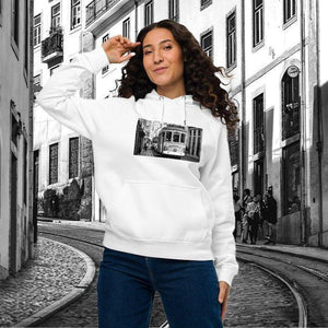 Woman wearing a white eco-friendly hoodie with a streetcar graphic, posing on a city street.