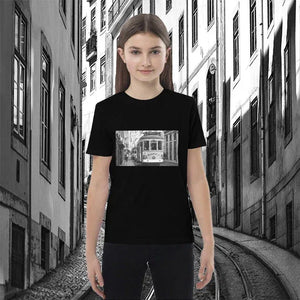 Child wearing black organic cotton t-shirt with tram street photo print, city street background