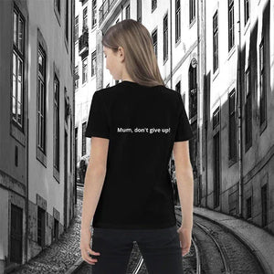 Child wearing black organic cotton t-shirt with 'Mum, don't give up!' text, city street background