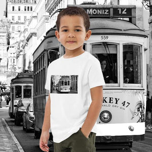 Child wearing white organic cotton t-shirt with tram print, city street background