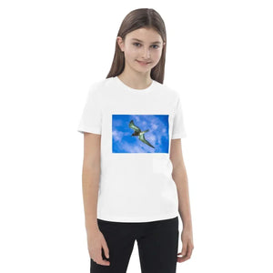 Child wearing white organic cotton t-shirt with flying bird print on blue sky background