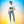 Woman wearing organic cotton unisex t-shirt with tropical beach print, casual jeans, sneakers.