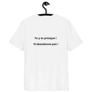 White organic cotton unisex t-shirt with French motivational text on the back, hanging on hanger