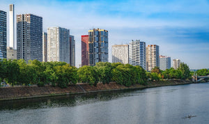 Image représentant les tours du Front de Seine à Paris, les arbres et la Seine sous un ciel bleu