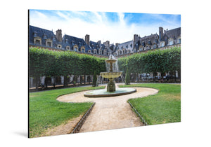 Tableau mural en aluminium représentant la fontaine, le jardin et les façades de la place des Vosges à Paris sous un ciel bleu