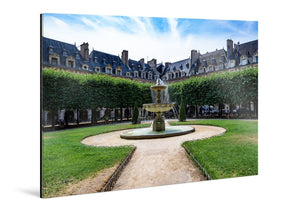 Tableau mural en plexiglas représentant une fontaine, le jardin et les façades de la place des Vosges à Paris sous un ciel bleu