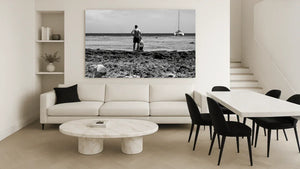 Modern living room with white sofa, marble coffee table, and large black and white seaside photo wall art.