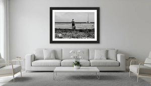 Modern living room with framed black and white photo of beach, man, and sailboat on wall