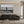Modern living room with black sofa, glass table, and large black-and-white seascape wall art