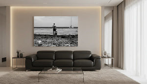 Modern living room with black sofa, glass table, and large black-and-white seascape wall art