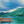 Wooden boat with paddle wheels on blue water, green lush island and mountains in background