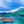 Wooden pedal boat on serene blue water with lush green island and cloudy sky