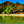 Tropical beachfront huts, clear turquoise water, palm trees, mountain view, vibrant scenery.