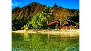 Tropical beachfront huts, clear turquoise water, palm trees, mountain view, vibrant scenery.