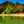 Tropical beach with clear water, palm tree, huts, and lush mountains under blue sky