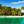 Tropical beach with palm trees, clear turquoise water, thatched huts, and blue sky